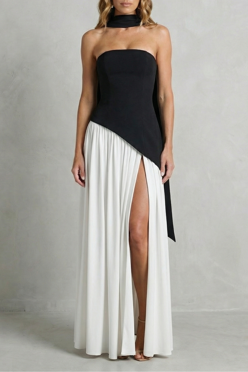 Black strapless formal gown with asymmetric drape and pleated skirt with high slit