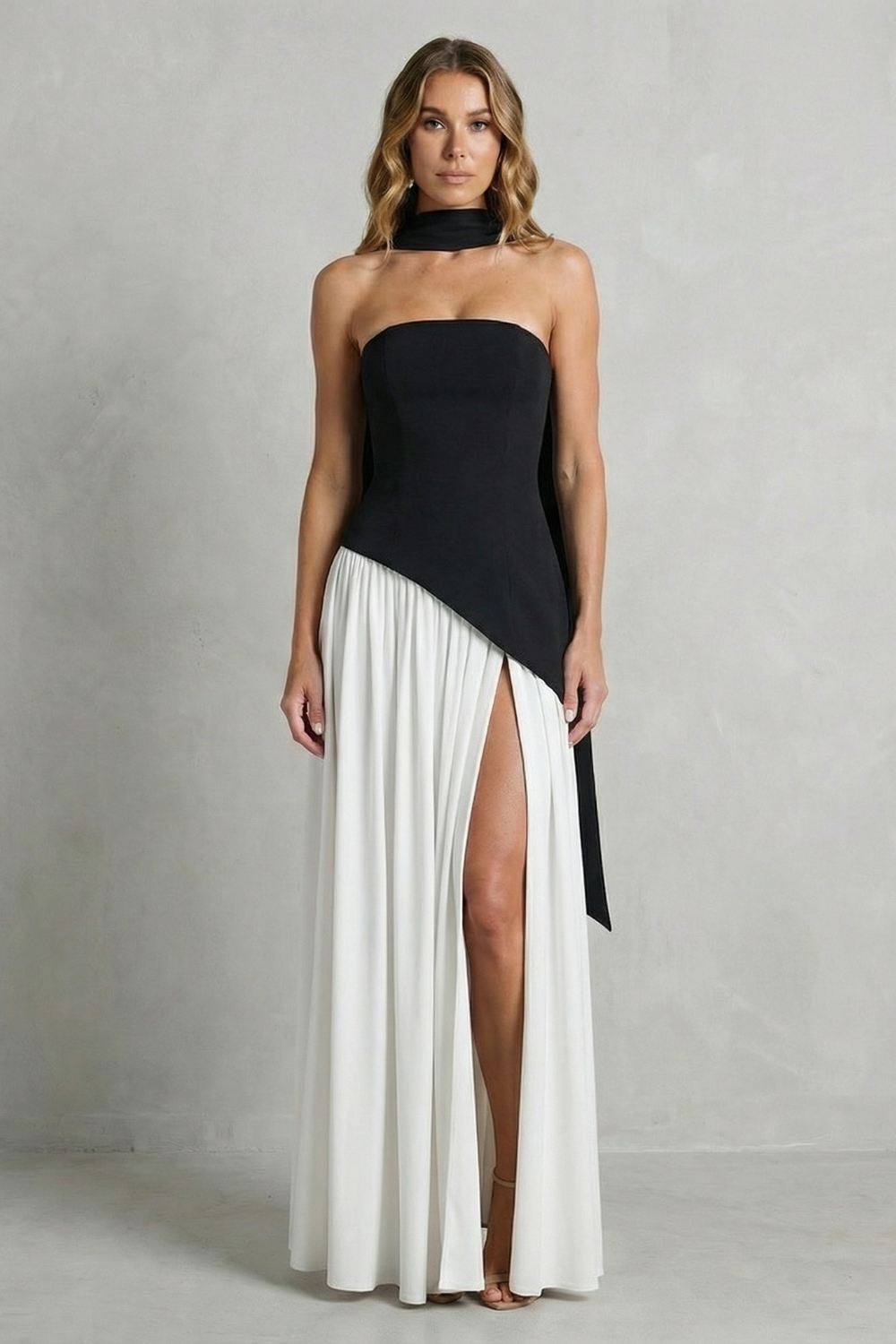 Black strapless formal gown with draped bodice and pleated skirt with leg slit