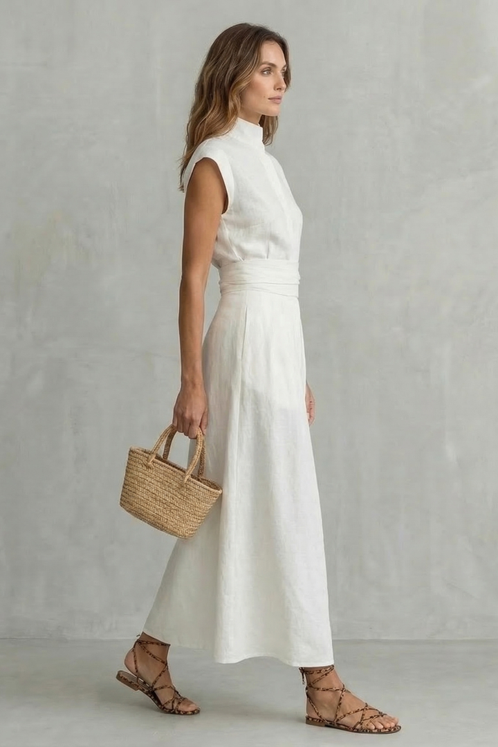 White sleeveless maxi dress with high neck and defined waist, side profile