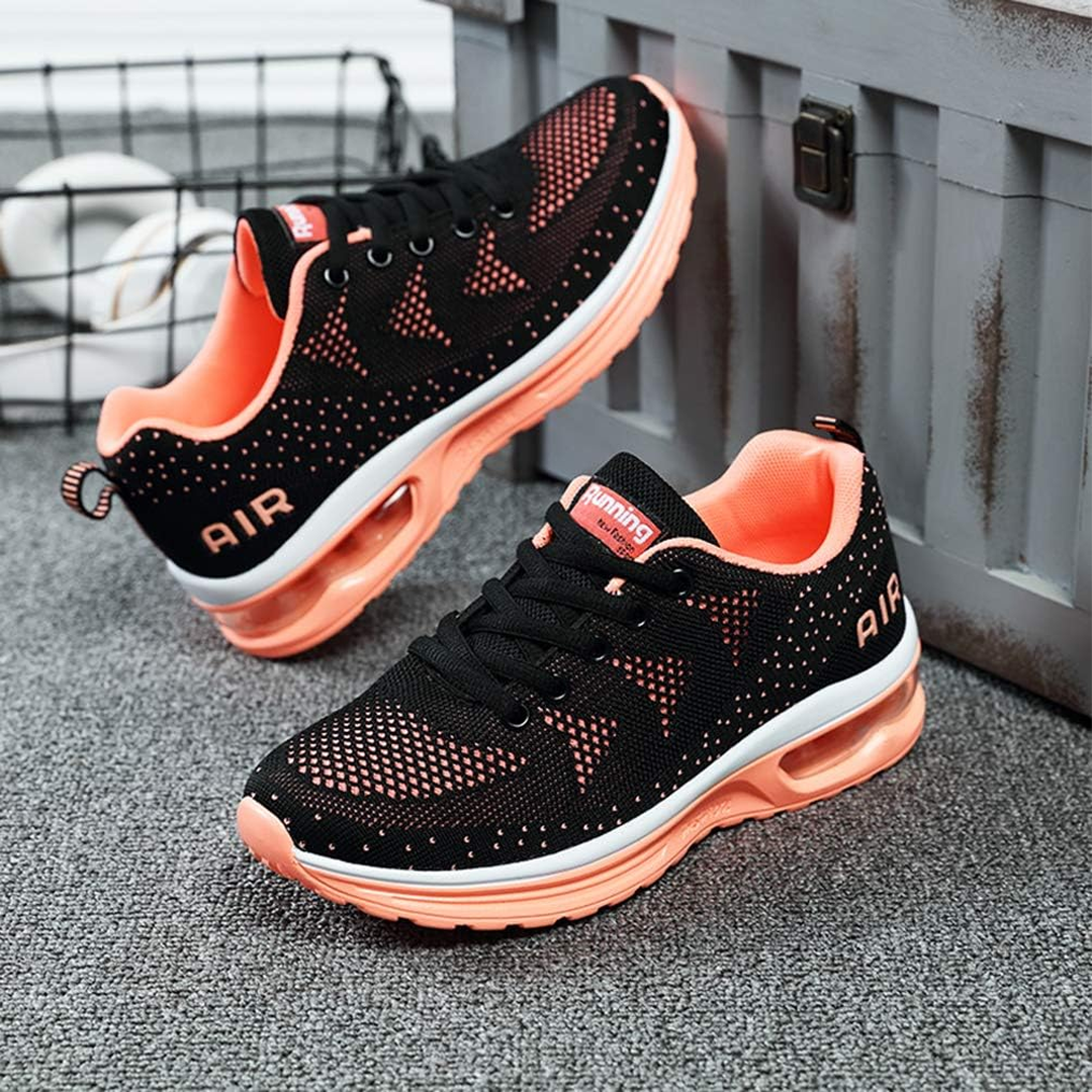 Black lace-up walking sneakers with orange collar and air-cushion sole, pair on ground