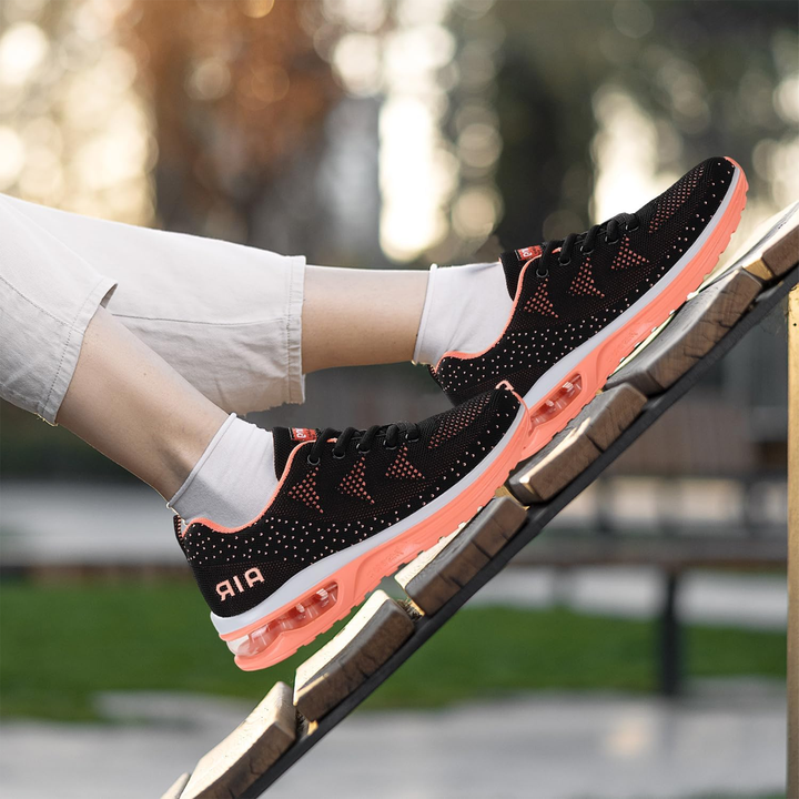 Black and orange knit walking sneakers with air-cushion sole, worn with white shorts