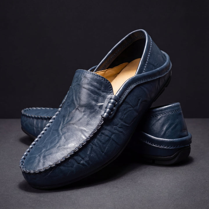 Dark blue leather loafer with moc toe and tassel-like stitching, slip-on