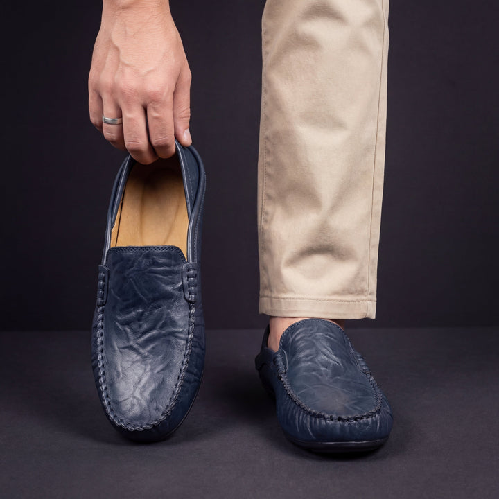 Navy blue leather loafer with moc toe stitching, slip-on worn with pants