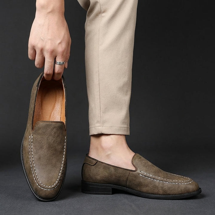 Khaki slip-on loafers on feet, rounded toe and contrast-stitched apron detail