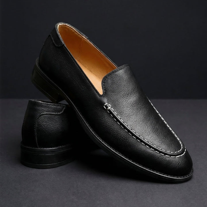 Black slip-on loafer with rounded toe, stitched apron, and dark rubber sole