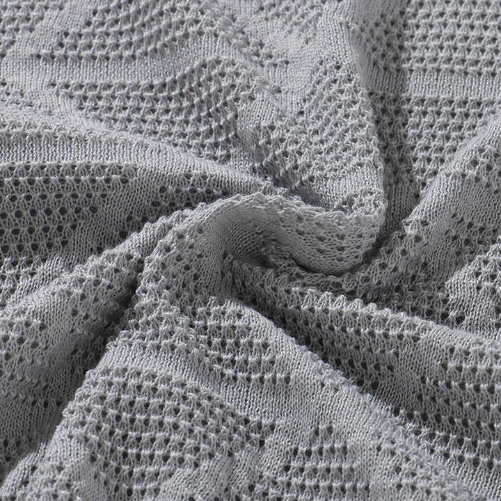 Grey knitted polo fabric close-up with geometric open-knit pattern