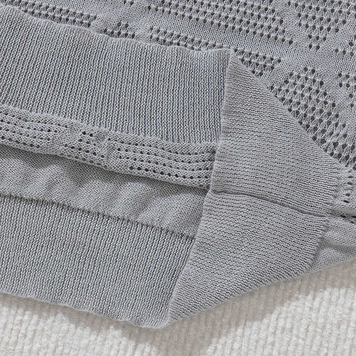 Grey knitted polo sleeve cuff and ribbed hem with open-knit texture