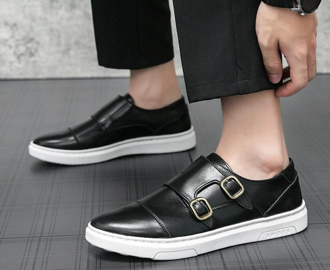 Black strap sneakers on foot with double buckle straps and white sole