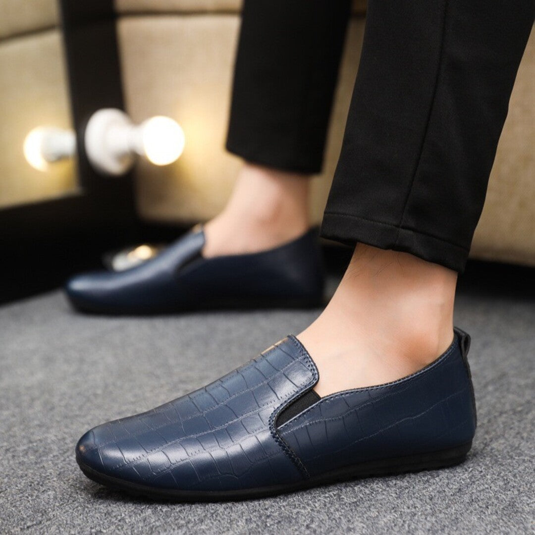 Navy blue croc-textured slip-on loafers with elastic gore panels on feet
