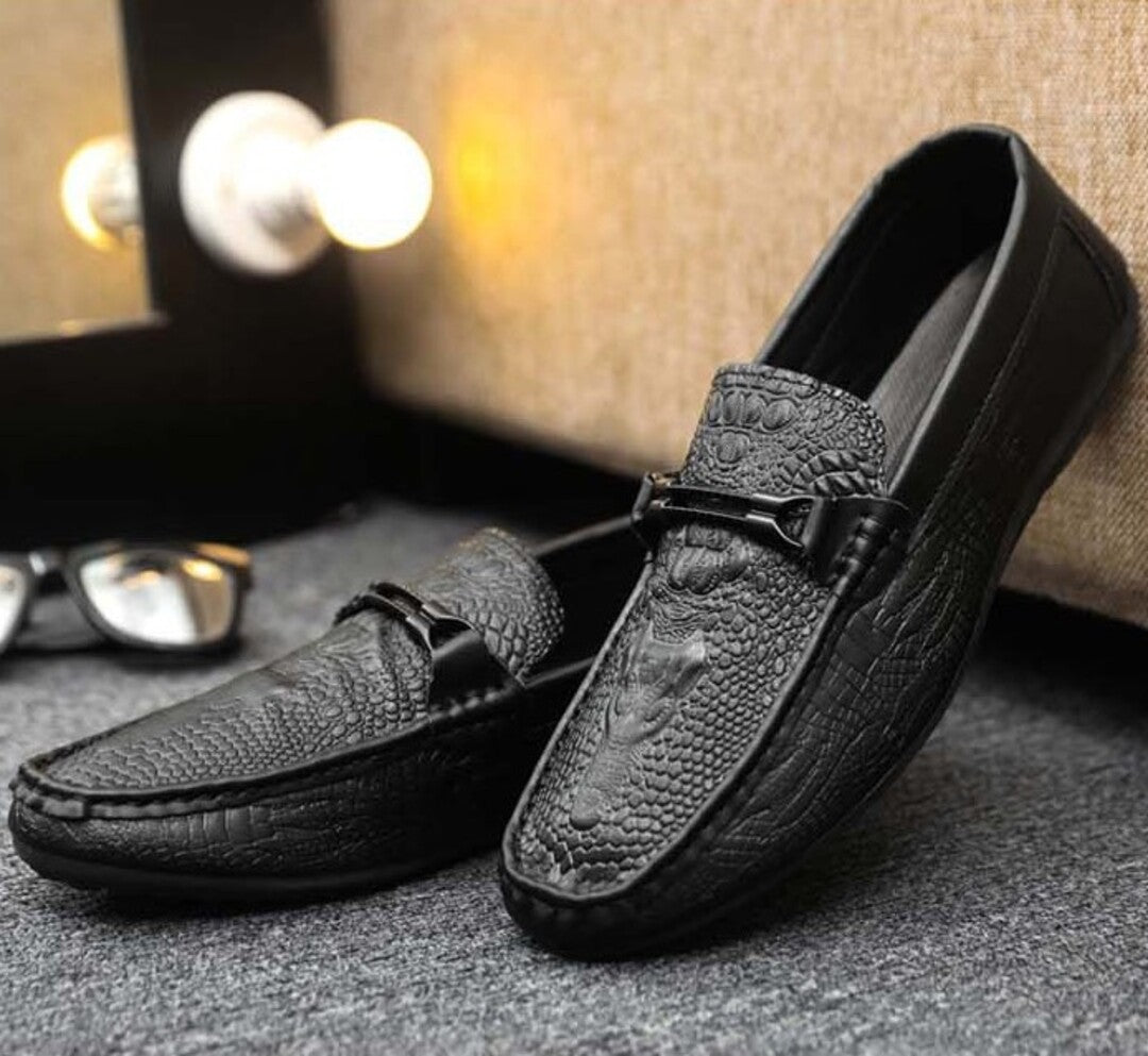 Pair of black croc-textured leather loafers with buckle strap and stitched toe