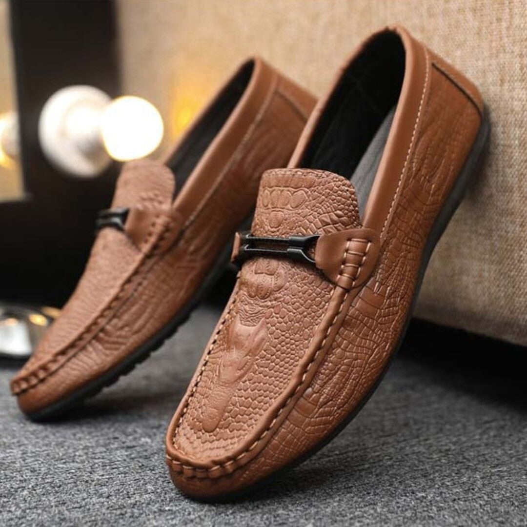Brown croc-textured leather loafers with black buckle strap and stitched seam detailing