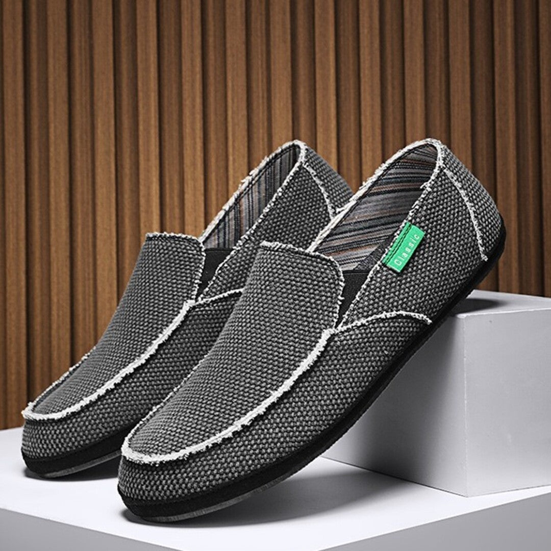 Black textured slip-on shoes with white stitching and cushioned moc-style toe