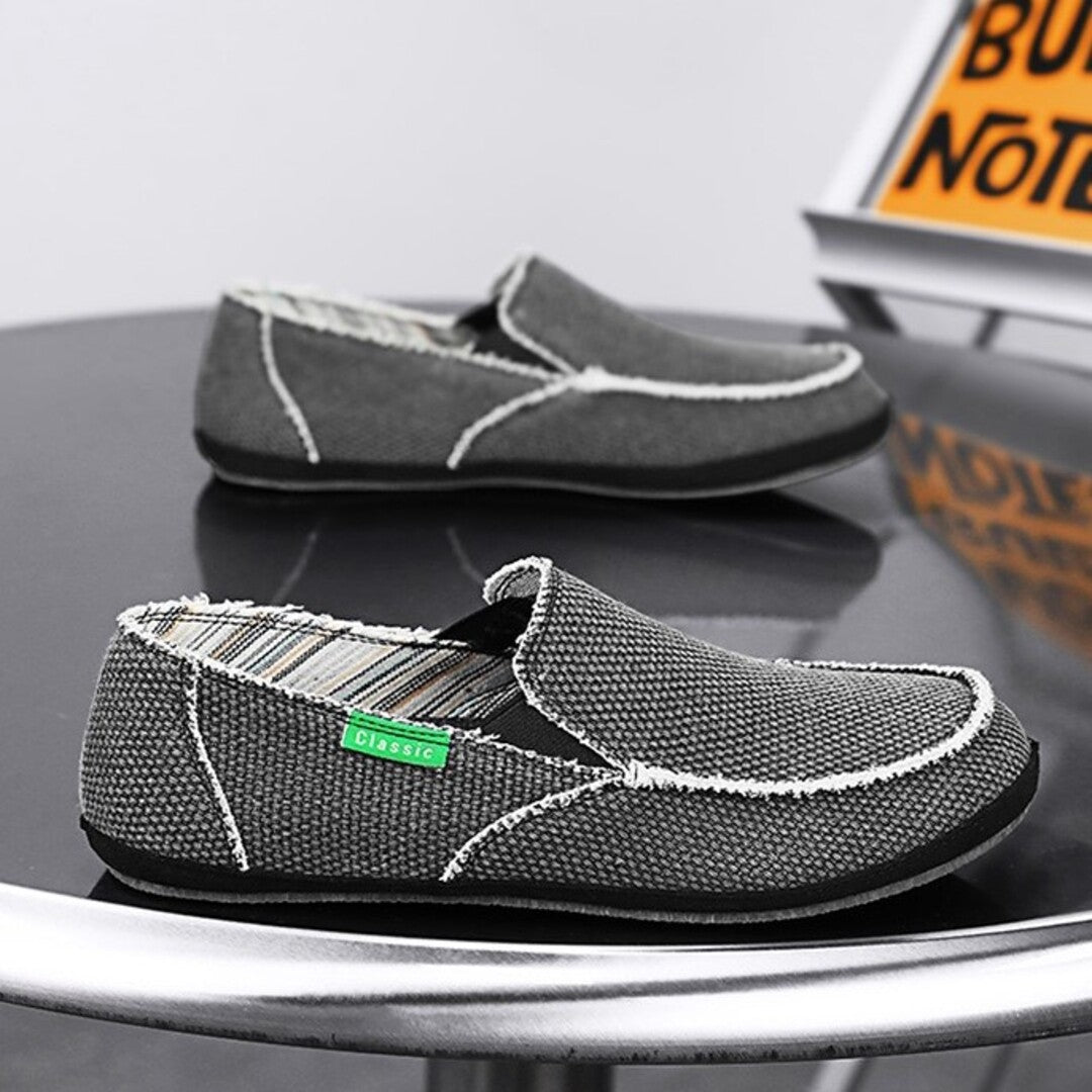 Dark gray textured slip-on shoes with white stitching and cushioned moc-style toe