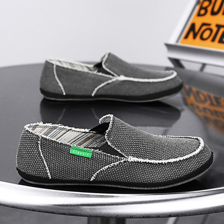 Dark gray textured slip-on shoes with white stitching and cushioned moc-style toe