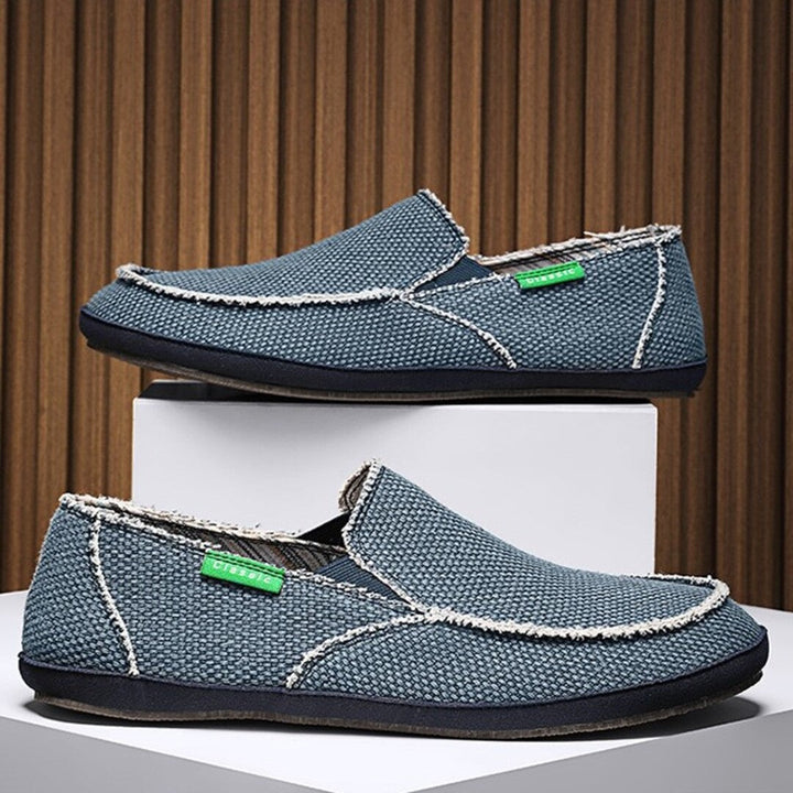 Blue textured slip-on shoes with white stitching and cushioned moc-style toe