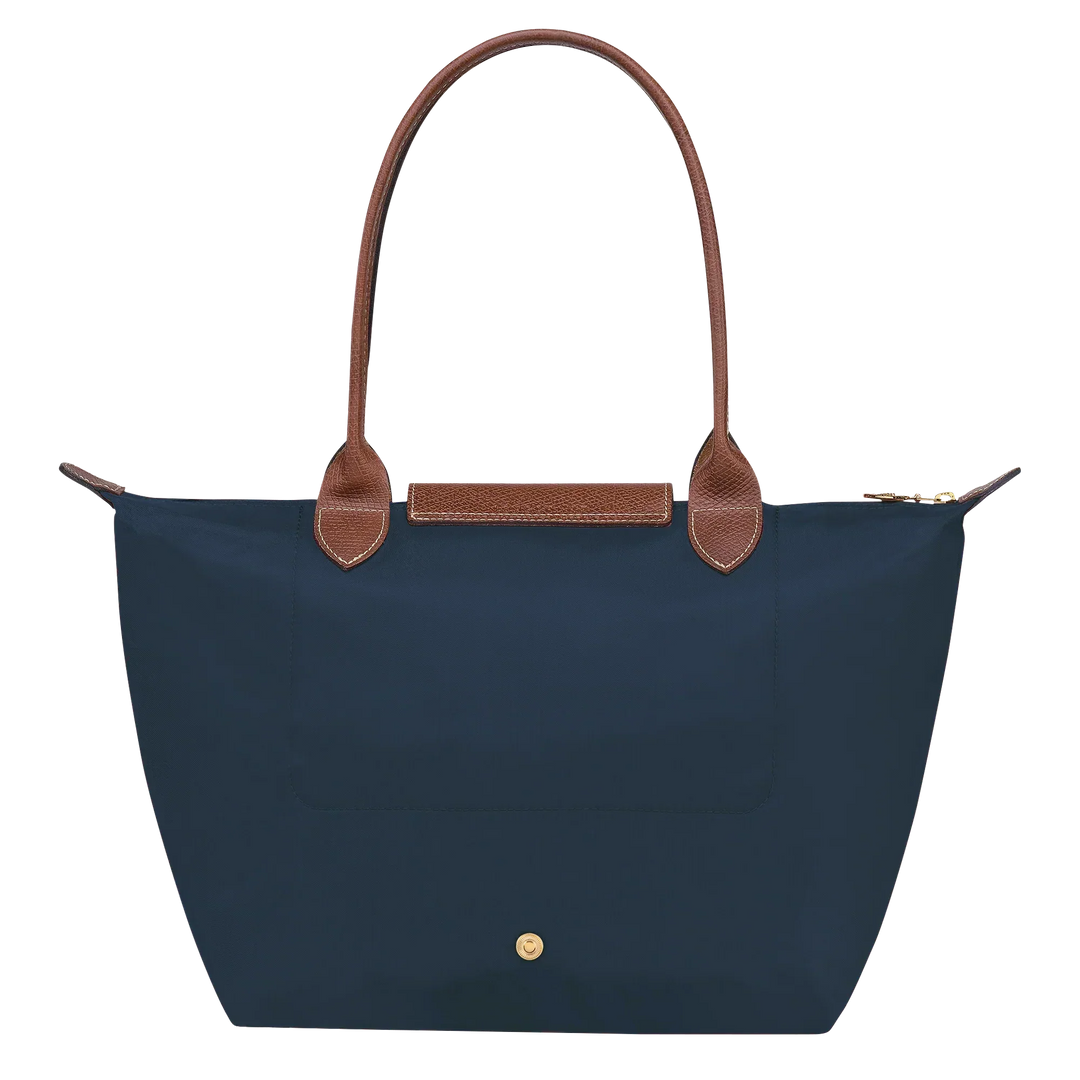 Navy medium tote with tan leather top handles, front snap pocket, and gold hardware