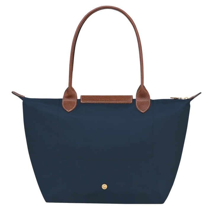 Navy medium tote with tan leather top handles, front snap pocket, and gold hardware