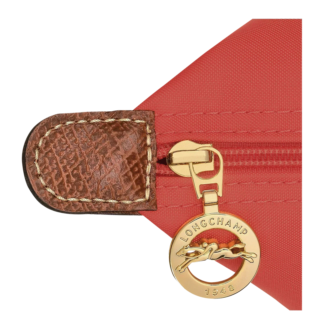 Gold-tone hardware detail on tomato tote with brown leather tab and logo medallion charm