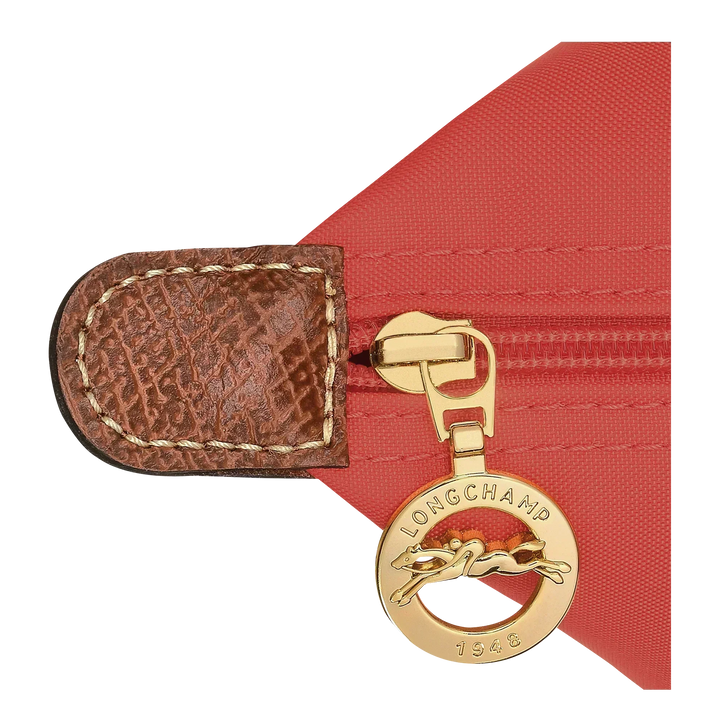Gold-tone hardware detail on tomato tote with brown leather tab and logo medallion charm