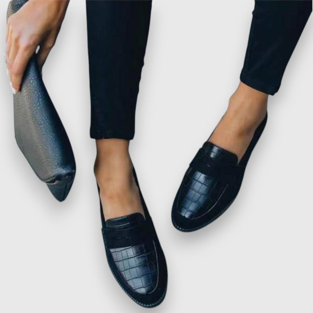 Black penny loafers with croc-embossed upper, shown close-up from front