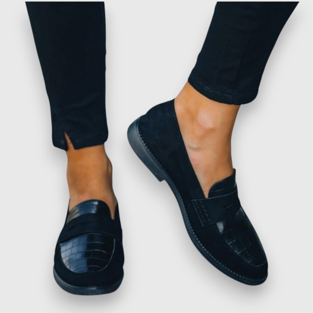 Black penny loafers, side view with stitched edge and low heel