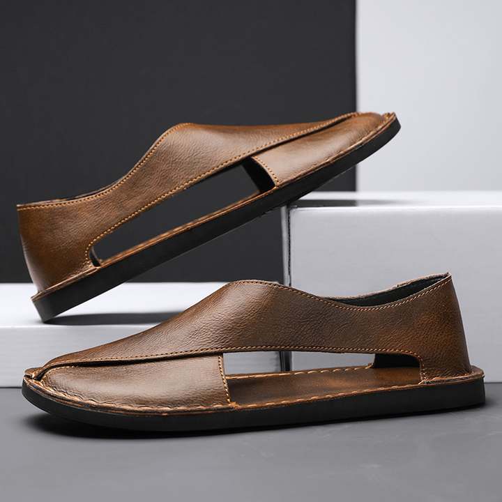 Brown leather open-toe slide sandals with stitched V strap and low dark sole.