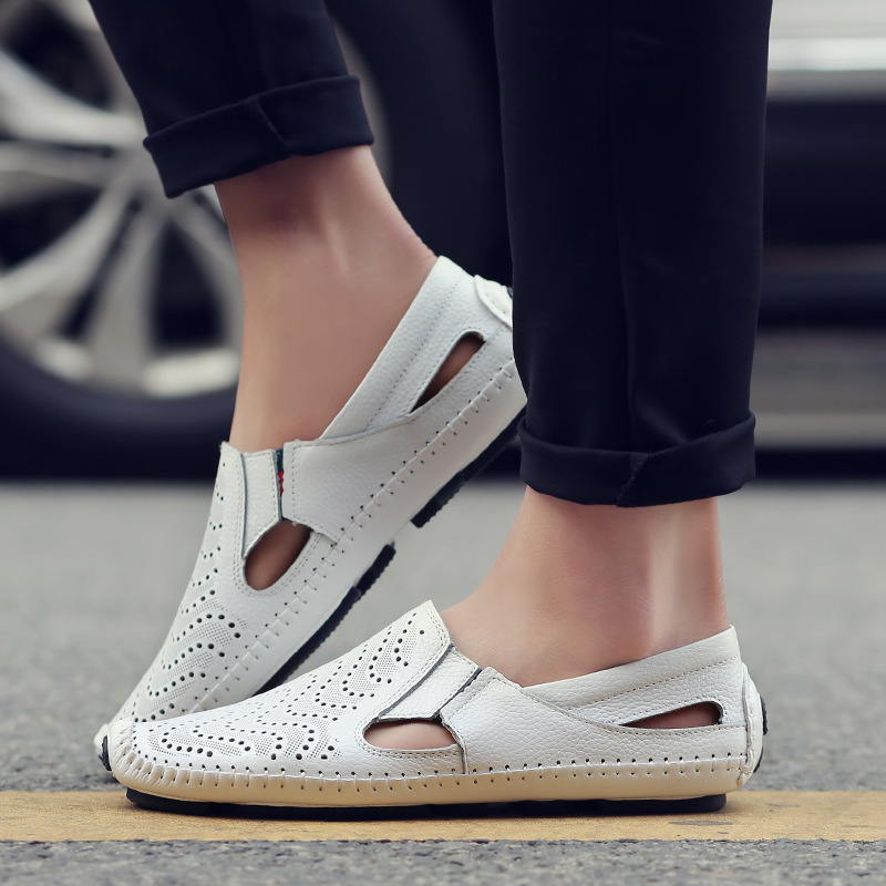 White slip-on sandals with perforations, cut-out sides, and tan sole trim on feet