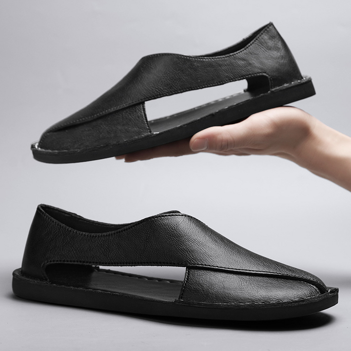 Black leather slip-on sandals with open side cutout and low flat sole