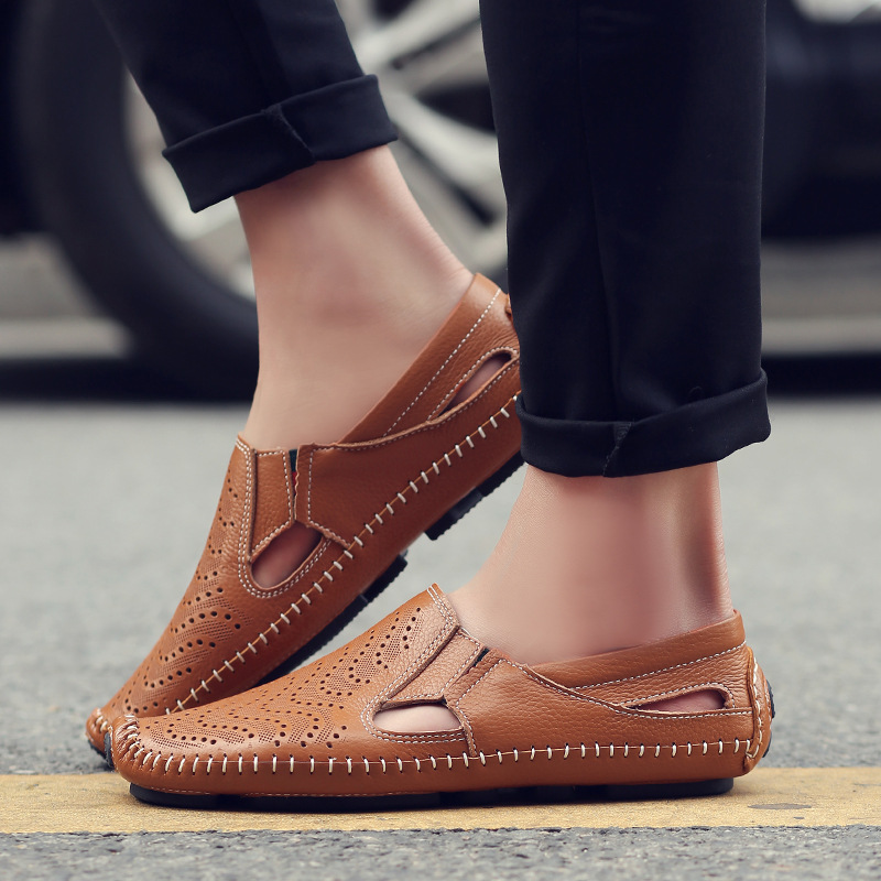 Tan perforated slip-on sandals worn with dark pants, low-profile stitched sole