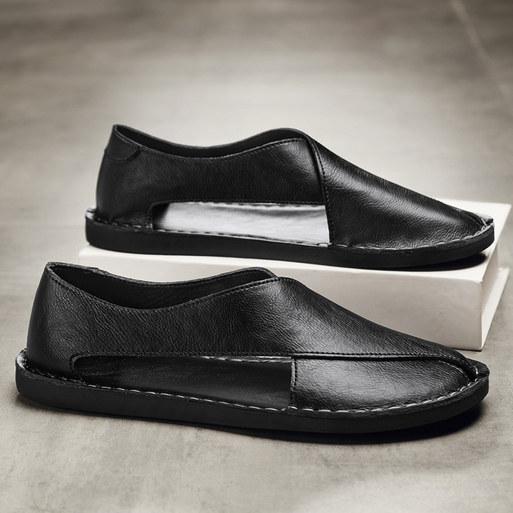 Black leather open-toe sandals on box, with stitched upper and low sole