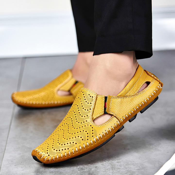 Yellow perforated slip-on sandals with moc toe on concrete, contrast stitched sole