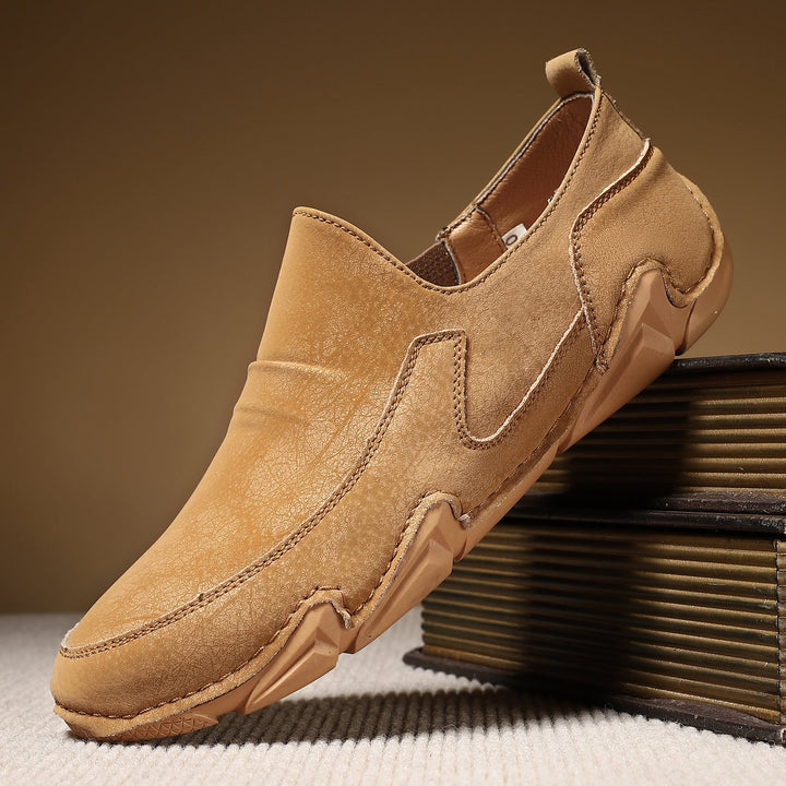 Tan slip-on loafers with moc-toe stitching and thick rubber tread sole.