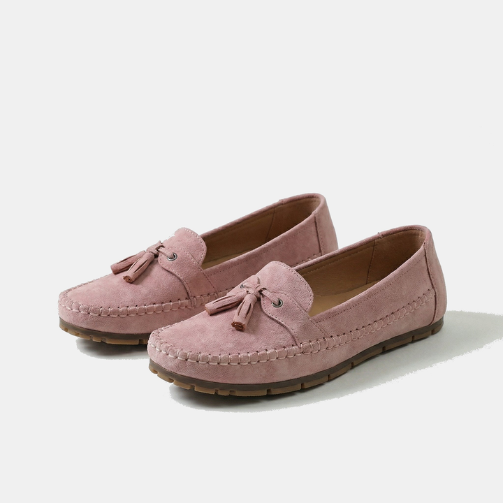 Pink suede tassel loafers with bow detail and moccasin-style stitching, flat sole.