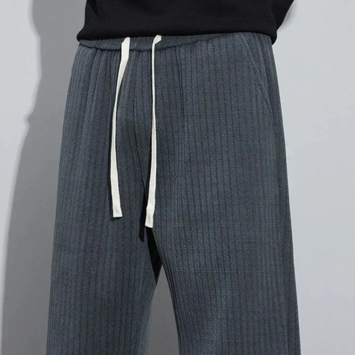 Charcoal Roman velvet pants close-up, elastic waistband and vertical textured fabric.
