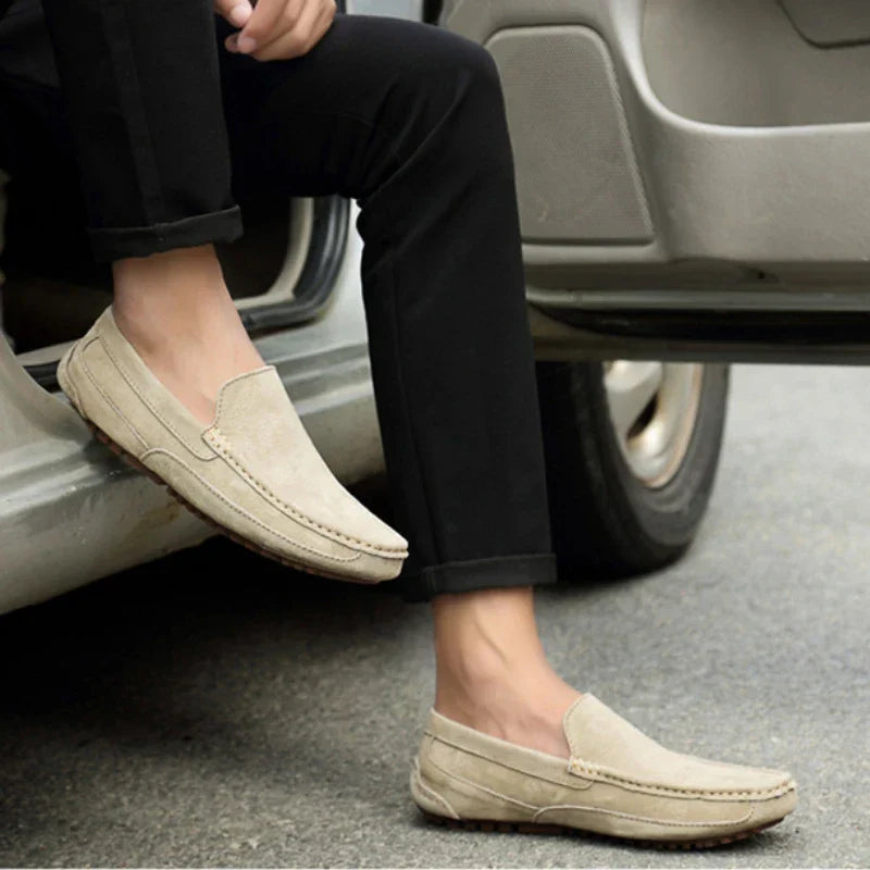 Stone suede slip-on loafer on a person’s foot with black pants