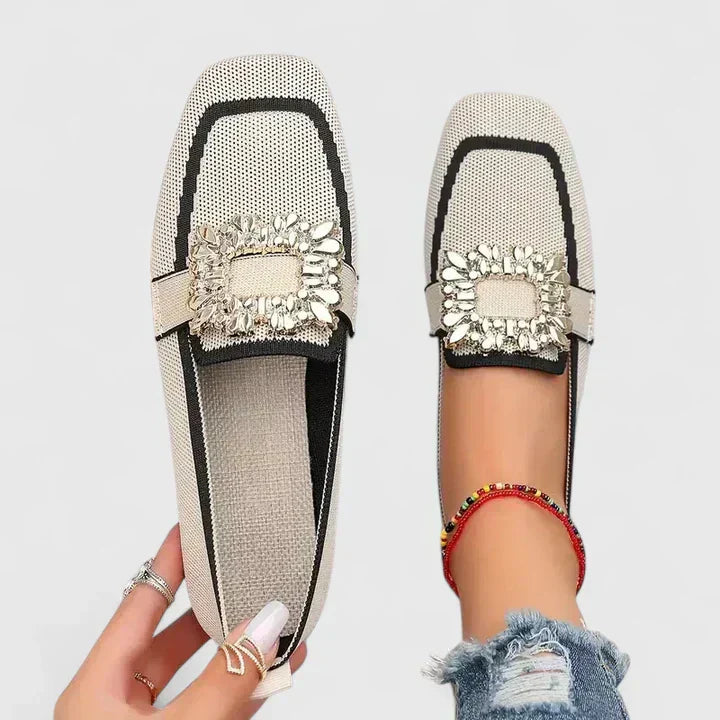 Cream square-toe flats with black trim and ornate gold jeweled buckle