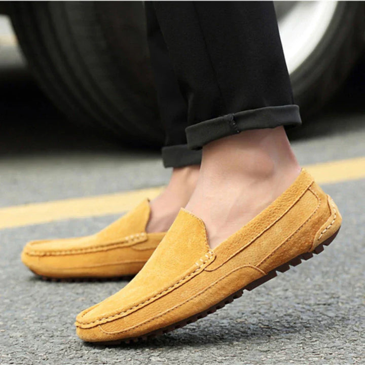 Yellow suede slip-on loafer on a person’s foot with black pants