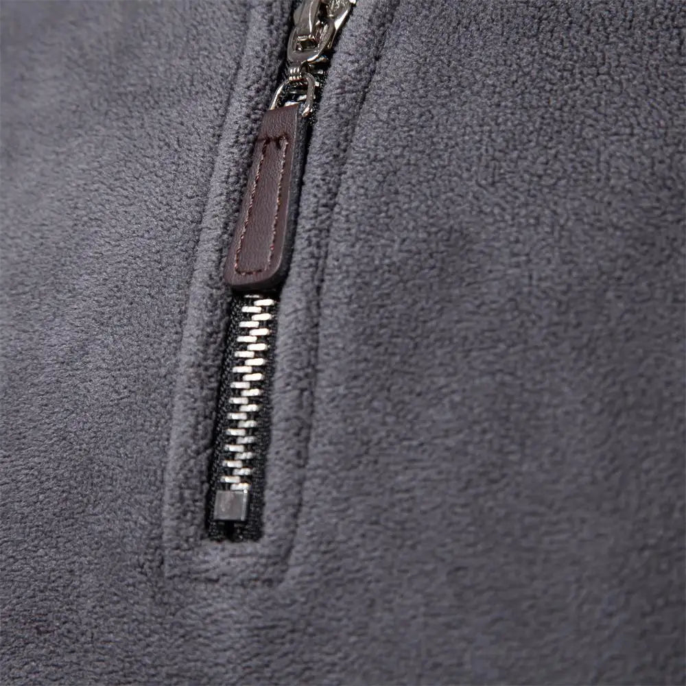 Dark gray fleece windbreaker jacket, close-up of front zipper pull and stitching