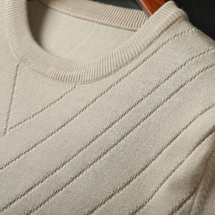 Beige cashmere knit close-up with ribbed crew collar and diagonal stitch lines