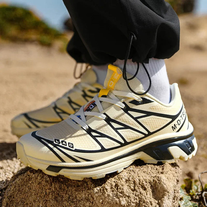 Women’s lace-up walking sneaker in beige and black with yellow pull tab on outdoor ground