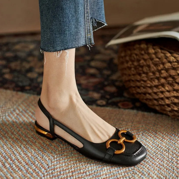 Women’s slingback flats in black leather with gold-tone buckle hardware and low block heel