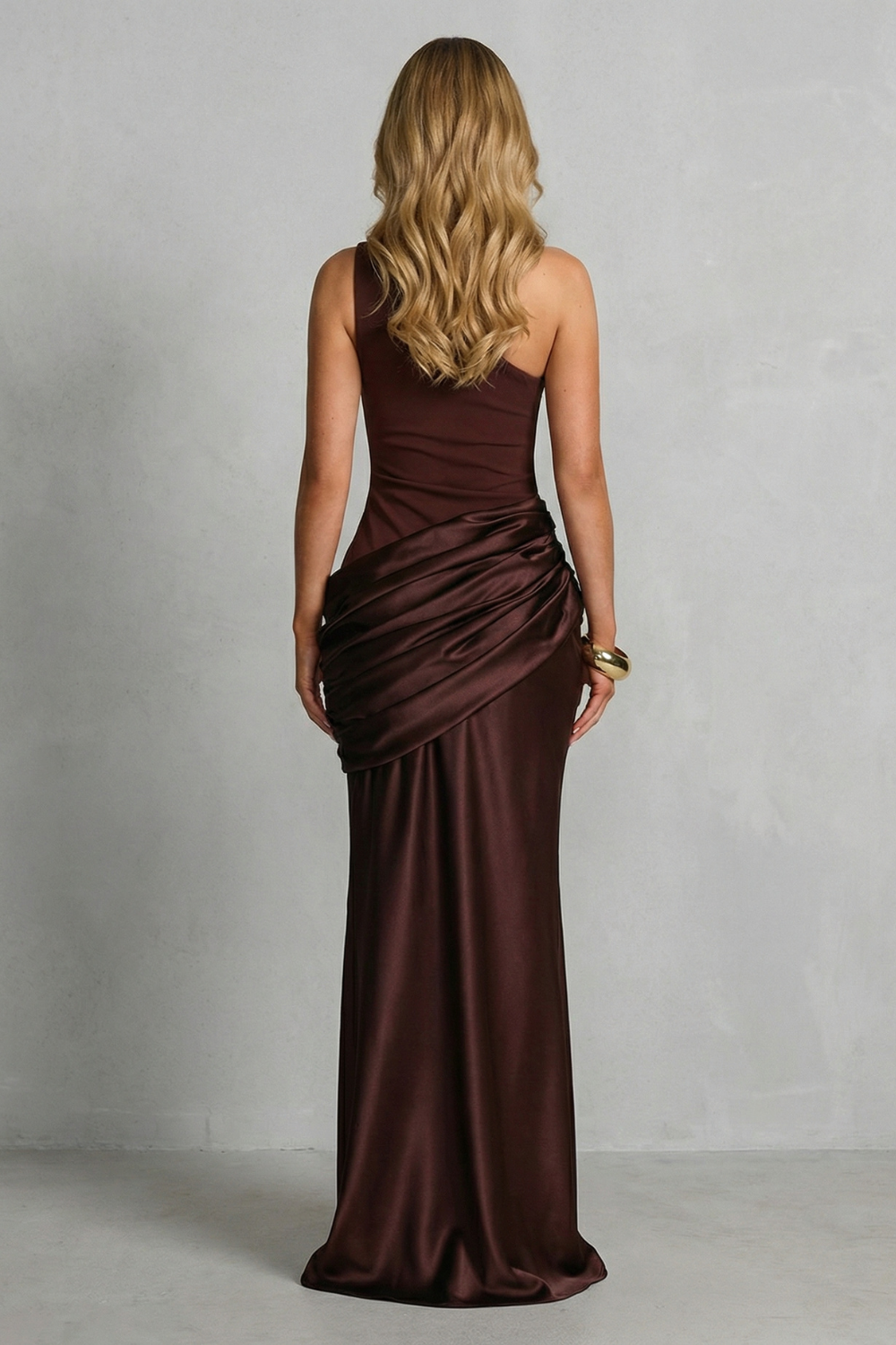 Back view one-shoulder maxi dress in dark brown satin, ruched hip and draped skirt