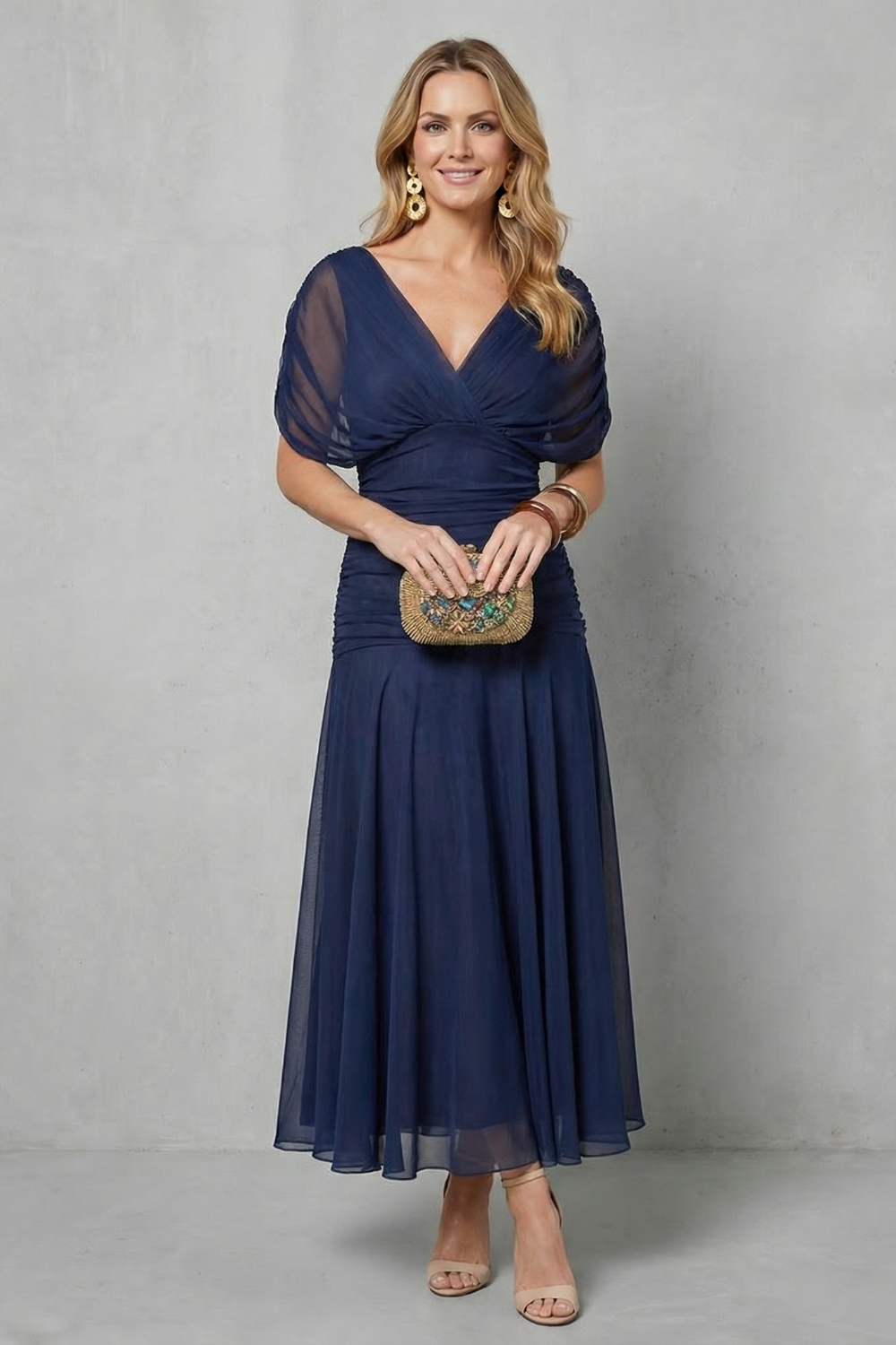 Navy off-shoulder maxi dress with draped V-neckline and layered pleated skirt