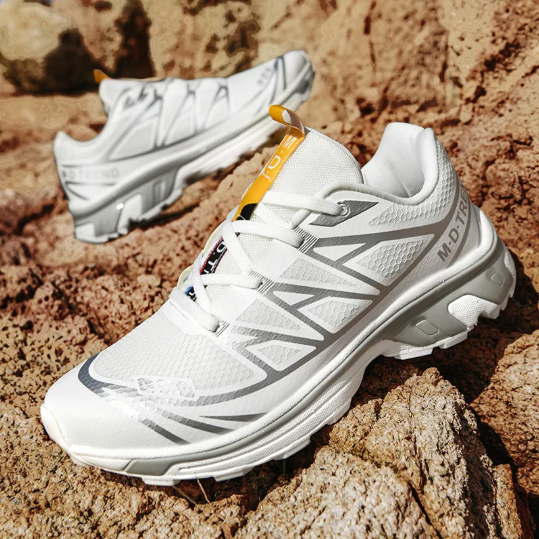 Women’s lace-up walking sneaker in white with black pattern and yellow pull tab on rocks