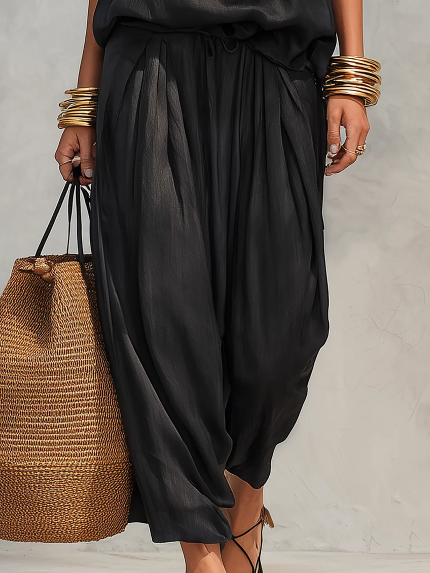Black pleated wide-leg pants with elasticized waist and flowing gathered fabric