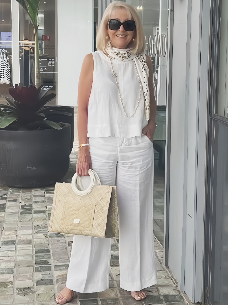 White sleeveless layered blouse top with high beaded neckline and wide-leg trousers