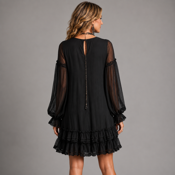 Black mini dress back view with sheer sleeves and long center tie, tiered ruffle hem