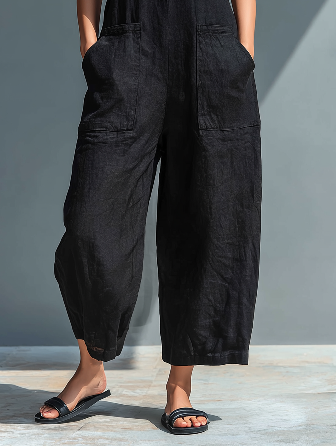 Sleeveless utility jumpsuit, black, lower view showing wide legs and patch pockets