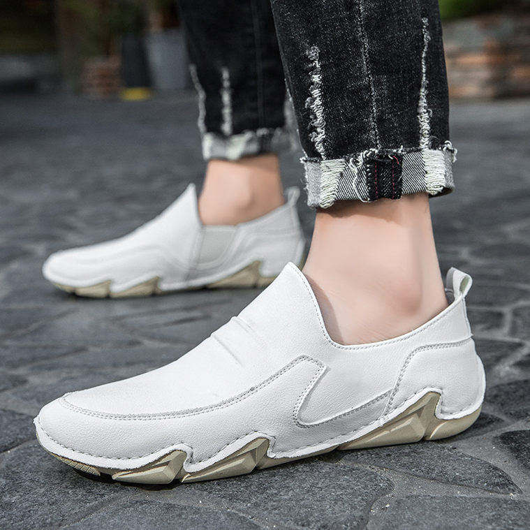 White slip-on loafers on model foot, moc-toe stitching and chunky rubber sole.