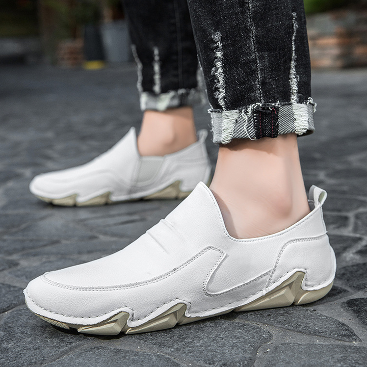 White slip-on loafers on model foot, moc-toe stitching and chunky rubber sole.